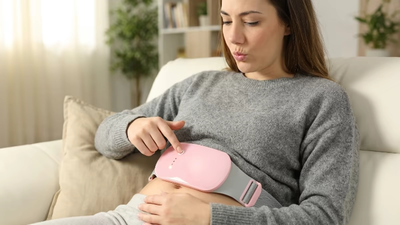 Cinturón para Cólicos: ¿Funciona? 8 Mujer seleccionando la temperatura del cinturón para cólicos menstruales desde el nivel más bajo para mayor seguridad